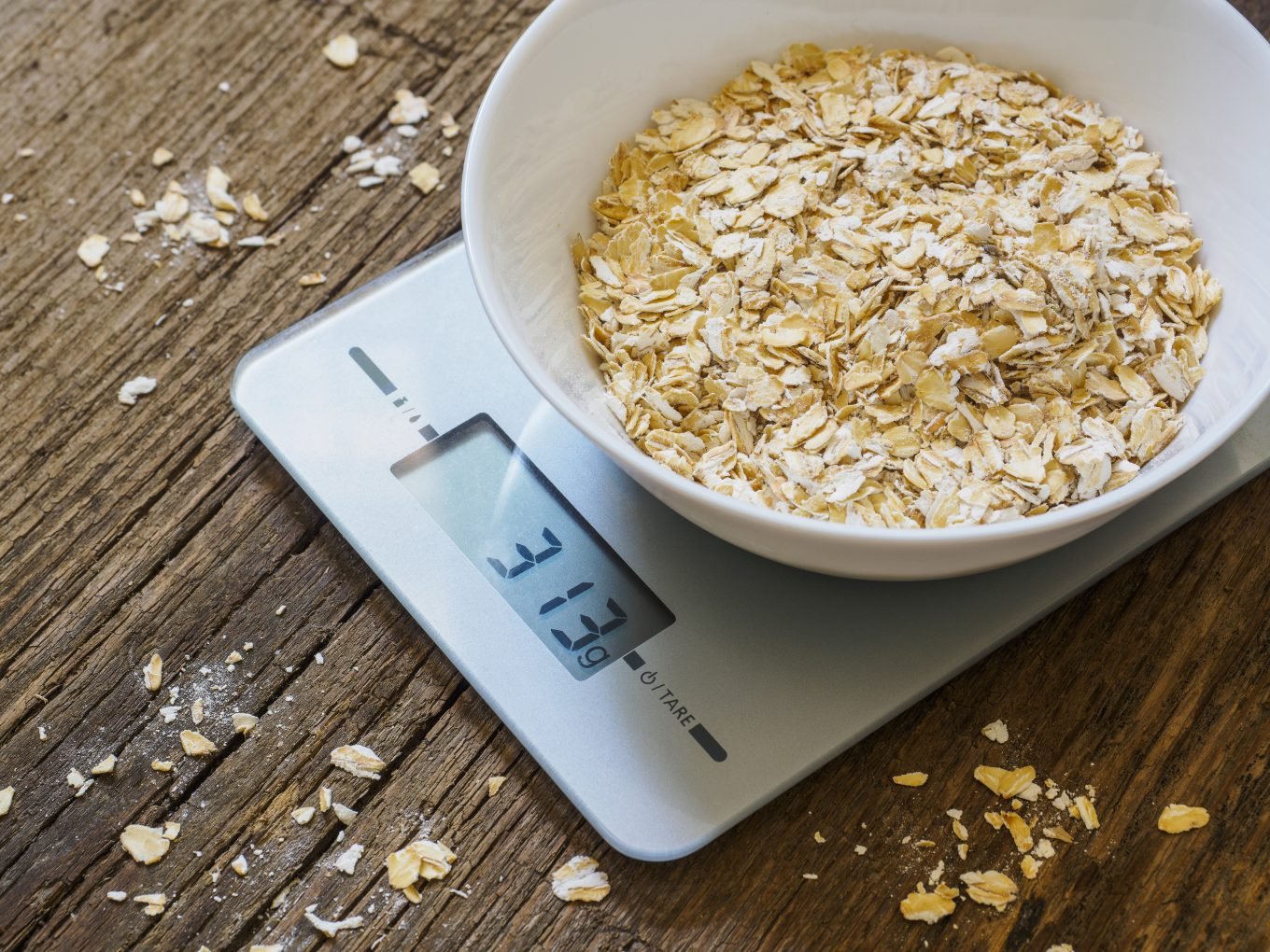 A bowl of oats sits on top of a digital kitchen scale which reads 313g.