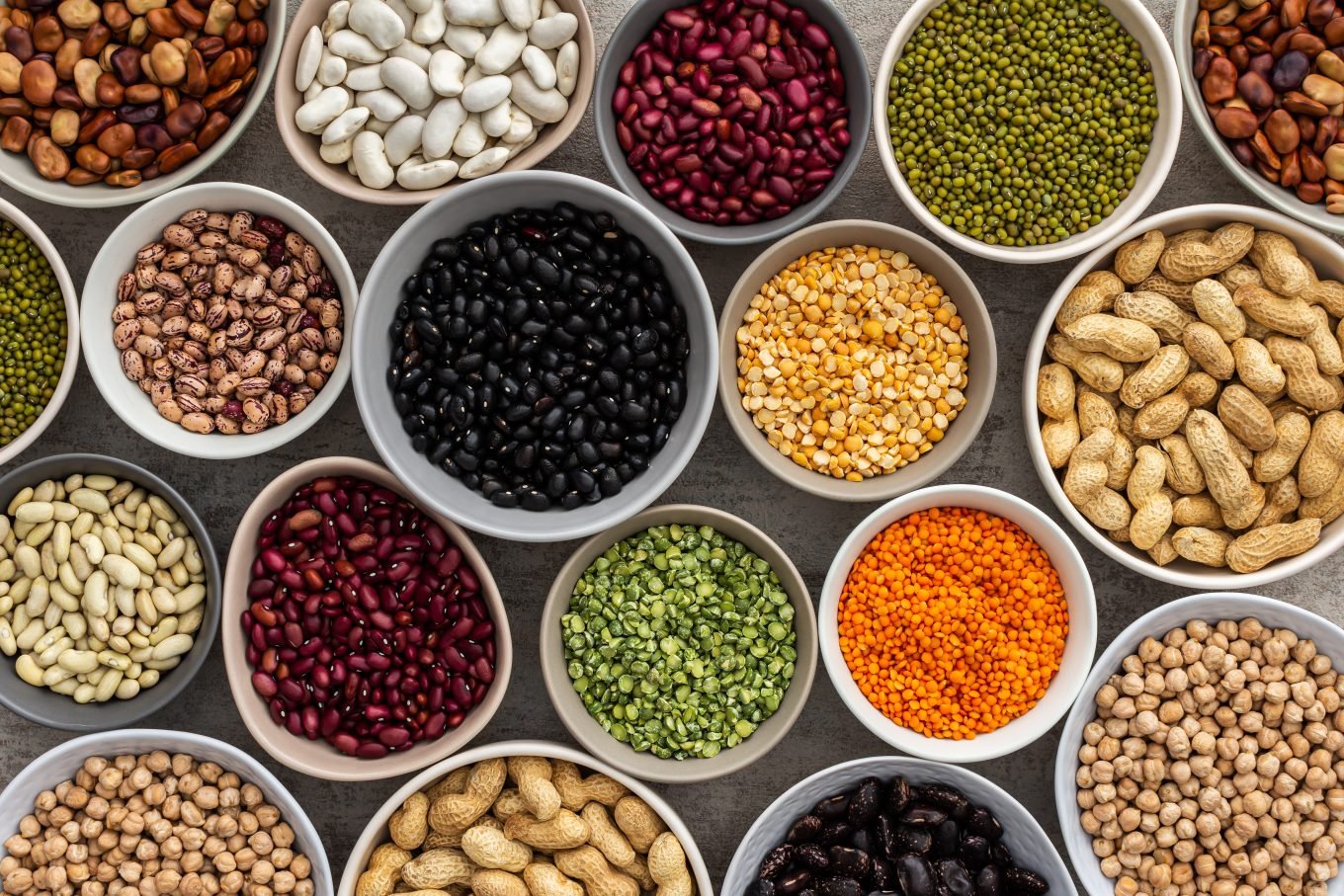A variety of bowls are filled with different pulses and legumes. 